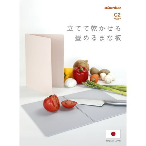まな板　抗菌　atomico　立てて乾かせる畳めるまな板　食洗機対応　日本製　ベージュ 折りたたまれた状態で立てかけられ、ベージュの表面が見える様子
