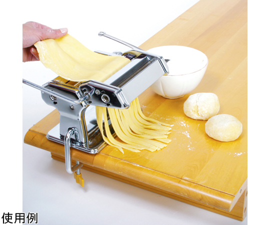 パスタマシーン PASTAMACHINE 金属製のパスタマシーンがテーブルに置かれ、クランクが回転されている様子