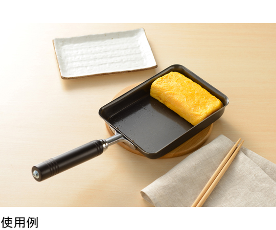 燕三 IH対応 鉄玉子焼13×18cm 黒い鉄製のフライパンがテーブルに置かれ、光沢のある表面が際立っている様子