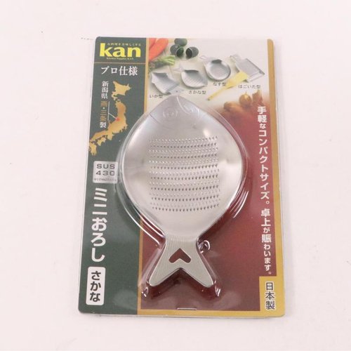 調理用品 kan 18-0ミニオロシ金 魚 金色の金属製器具が立てて置かれている様子、細長い形状が強調されている。