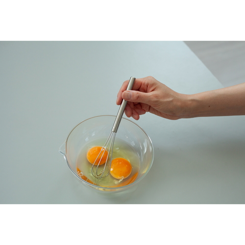 ミニ泡立て器　and　ステンレスミニ泡立て 持ち手がついたステンレス製の泡立て器が横向きに置かれている様子