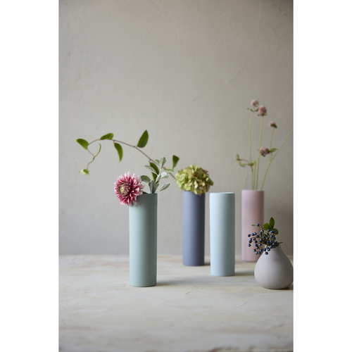 花瓶　AYA　フラワーベース　ロング　S　陶器　ピンク やや斜めの角度から捉えた、光沢のある陶器の長い花瓶が置かれた様子