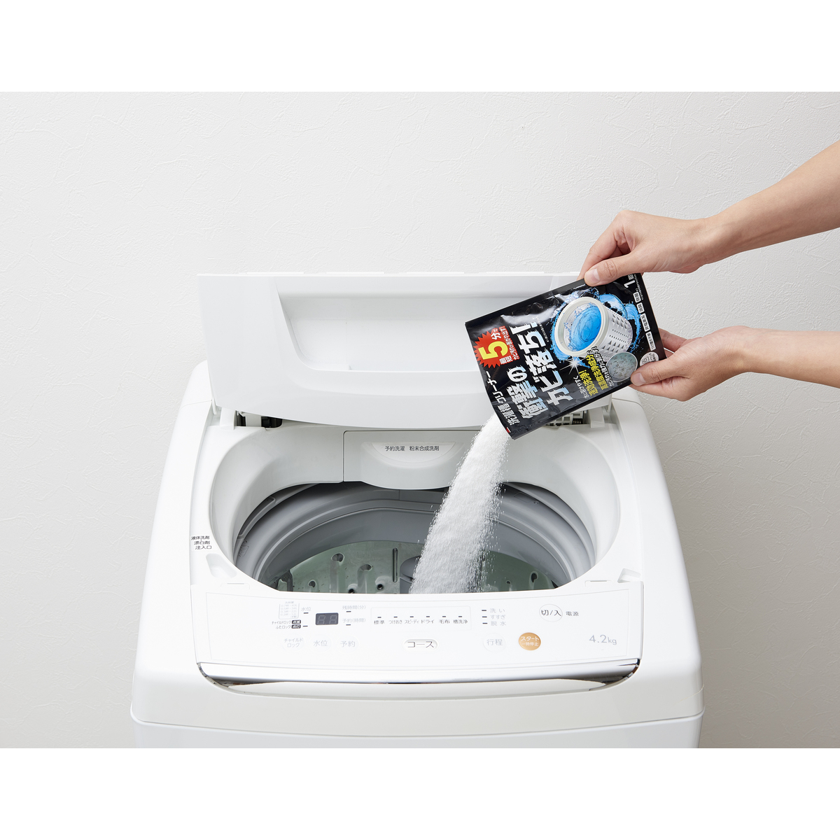 洗濯機洗剤　コインランドリーの洗濯機クリーナー 透明なボトルに入ったクリーナー、ラベルには洗浄効果を示すグラフィックが描かれている