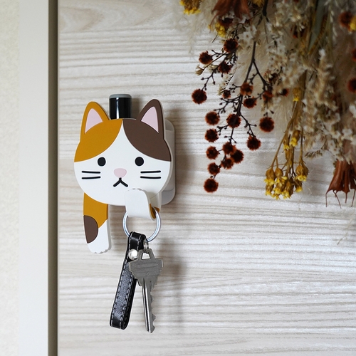 フック　吸着　スティッキーフックポケット　アニマル　ミケネコ 猫の顔を模したデザインのフックが明るい背景に取り付けられている様子