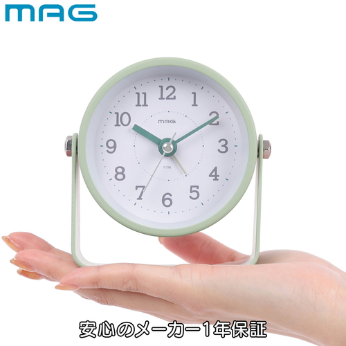 置き時計　電子音目覚まし時計　モナカ　グリーン 緑色の目覚まし時計がテーブルの上に置かれ、デジタル表示が明るく光っている様子。