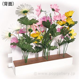 ガーベラ垣根アレンジ 鮮やかな色合いの花が垣根から垂れ下がっている様子