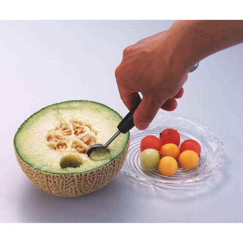 フルーツボーラー フルーツくり抜きスプーン 野菜くり抜型 金属製のスプーンが手に持たれ、刃先が果物をくり抜こうとしている様子