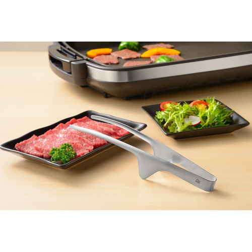 おきラク焼肉トング ハンドル部分がカーブしたトングが横向きに置かれている様子