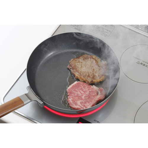 フライパン 両面エンボス加工 鉄製フライパン 26cm IH対応 表面がエンボス加工された鉄製のフライパンが手に持たれ、ハンドルが斜めに見える状態