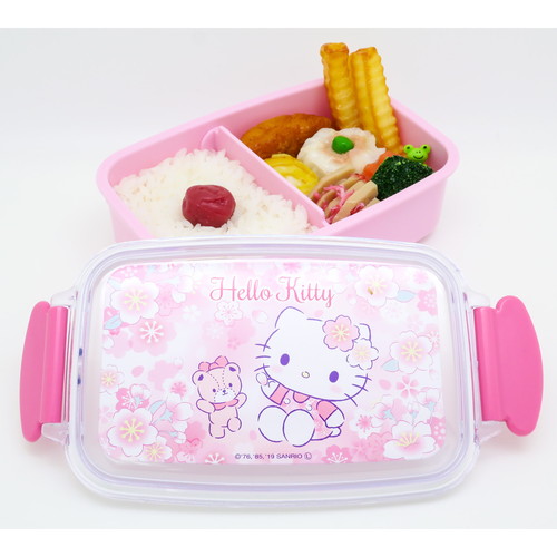 お弁当箱　1段　ハローキティ　サクラ　500ml　仕切り付　ランチボックス　子供 ピンク色の背景にハローキティのデザインがあしらわれたお弁当箱の正面が見える状態。
