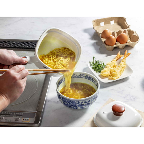 角型片手鍋　ホーロー四角いお鍋　麺ごこち　14　X　14　cm 光沢のあるエナメル仕上げの四角い鍋がテーブルの上に置かれている様子