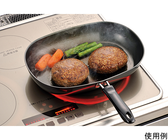 鉄製オーバルフライパン 黒い鉄製のオーバルフライパンがテーブルに置かれ、光沢のある表面と持ち手が見える状態