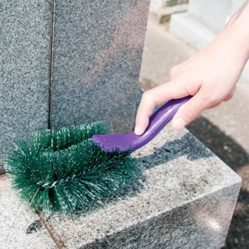 お墓洗い　墓石用角洗いブラシ 黒い握り手が付いた長いブラシが立てて置かれている様子