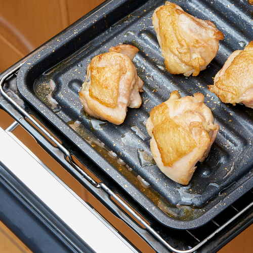 グリルのお手入れ簡単魚焼きトレー　ワイド シルバーのトレーがグリルで食材を焼いている様子、周囲に余裕のあるデザイン。