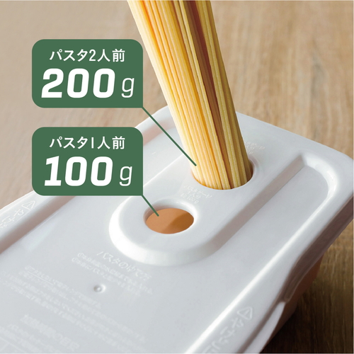 電子レンジ調理器　atomico　レンジで簡単調理ポット　アイボリー アイボリーのカラーで、蓋をした状態の横向きポットが見えるテーブル上の様子