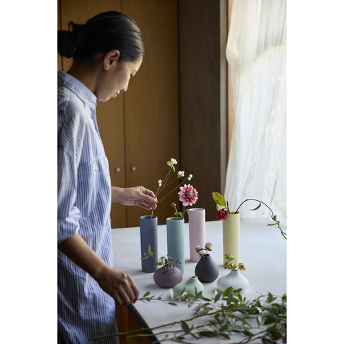 花瓶　AYA　フラワーベース　ロング　S　陶器　ピンク 滑らかな曲線を持つピンクの陶器製花瓶が横向きに置かれ、光沢感が際立つ様子